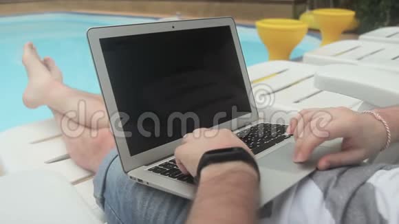 池畔男性自由职业者的特写正在为笔记本电脑做一个项目视频的预览图