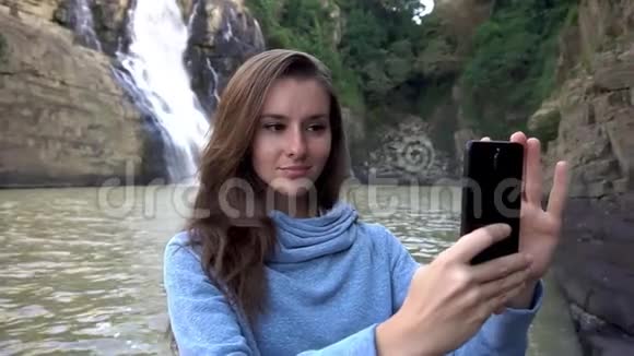 越南达拉特瀑布附近的女人用智能手机自拍视频的预览图