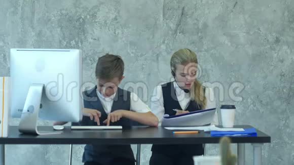 小男孩和穿着西装的可爱女孩一起在办公室工作视频的预览图