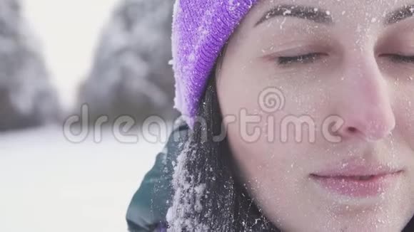 戴着紫色帽子的女孩在冬天森林的背景下看着摄像机海霜视频的预览图