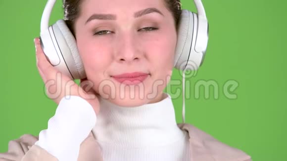 女孩在耳机里听悠扬的歌曲绿色屏幕快关门慢动作视频的预览图