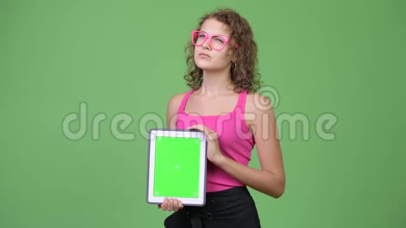年轻快乐美丽的书呆子女人一边看数字平板电脑一边思考视频的预览图