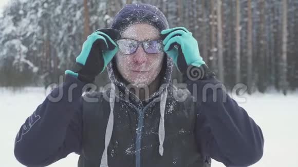 一个冻僵的人在冬天的森林里摘下眼镜在一场暴风雪之后被雪覆盖了视频的预览图