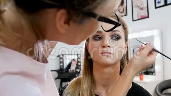 特写慢动作视频的专业化妆师绘画眼睛和涂抹睫毛膏Visagist准备模型视频的预览图