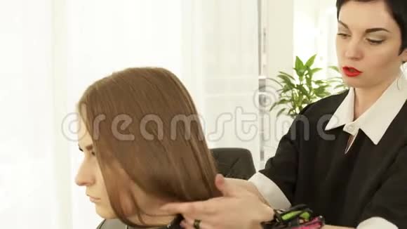 发型师在美发沙龙理发前触摸女性头发并喷水女性美容发型视频的预览图