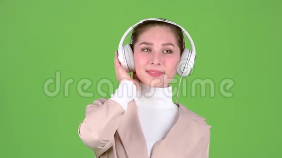 女人在耳机里听悠扬的歌曲绿色屏幕慢动作视频的预览图