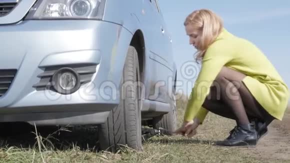 性感的金发女人在农村路上的车上试着换轮子4K视频的预览图
