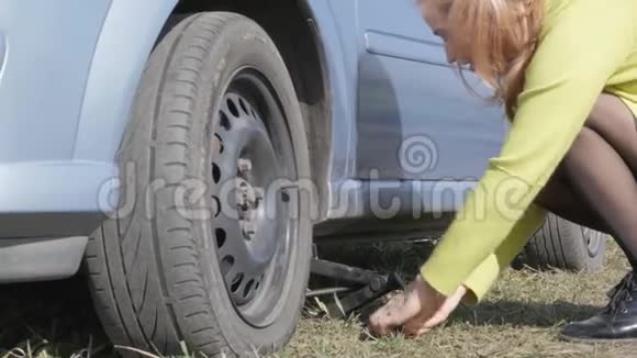 性感的金发女人在农村路上的车上试着换轮子4K视频的预览图