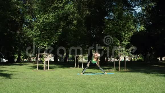 活跃的女性在草地上的城市公园锻炼和伸展瑜伽视频的预览图