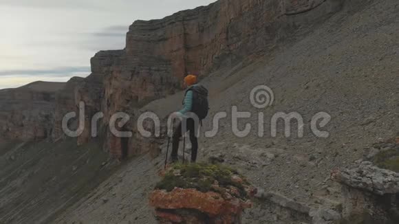 从一个年轻的成年女子手背背包回到史诗脚下的岩石顶部视频的预览图