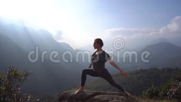 瑜伽在山崖锻炼和热身的女人视频的预览图