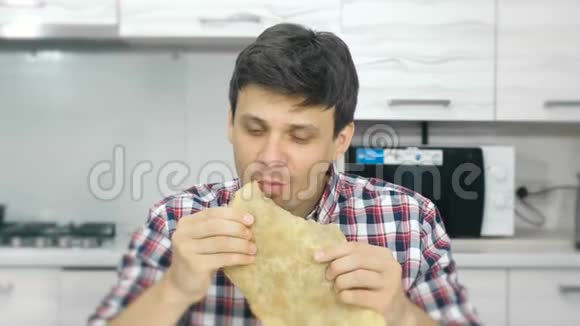 穿格子衬衫的年轻人吃一大块有食欲的奶酪视频的预览图