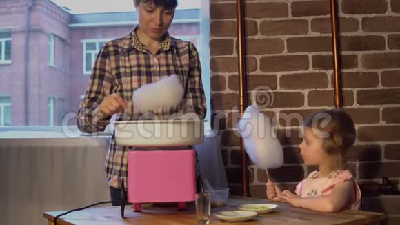 一位年轻的母亲在一台特殊的机器上为一个小女儿做棉花糖视频的预览图