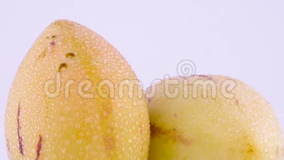 用水滴对两种成熟的黄色佩皮诺水果的上部进行宏观拍摄在转盘上慢慢旋转视频的预览图