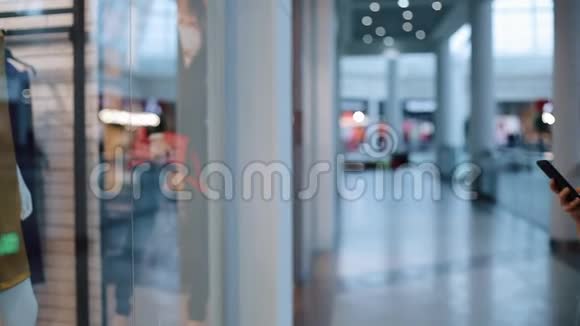 女孩在一家购物中心的橱窗前在电话上交谈并在智能手机上拍摄一段视频视频的预览图