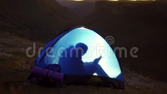 孤独的女人在帐篷里露营他用电话视频的预览图