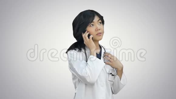 漂亮的亚洲女医生穿着实验室外套用听诊器在白色背景下用手机说话视频的预览图