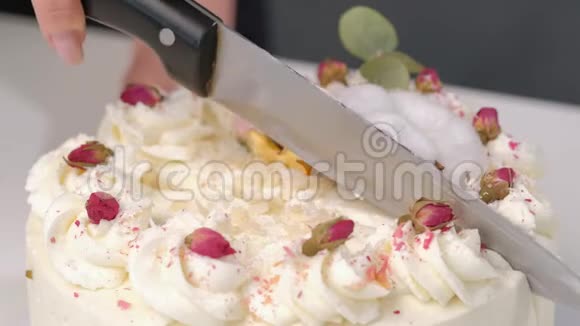 一个公寓用一把大刀切一个漂亮的新鲜装饰的白色蛋糕视频的预览图