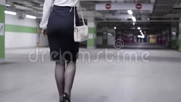 车库里带马尾白衬衫和黑裙的可爱女性的后景视频的预览图