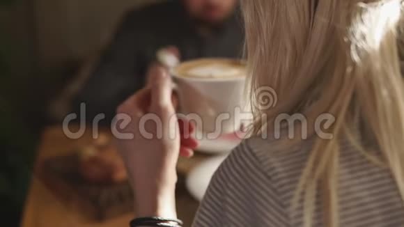 年轻女子手里拿着一杯热卡布奇诺她在一家餐馆吃饭视频的预览图