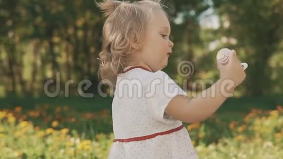小微笑的女孩吹着肥皂泡快乐童年概念视频的预览图