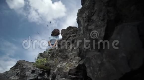 坐在巨大岩石上的女人视频的预览图