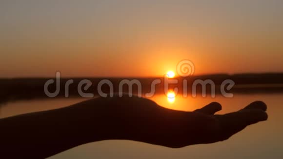 双手捧着太阳在手心美丽的晚霞在水面上视频的预览图
