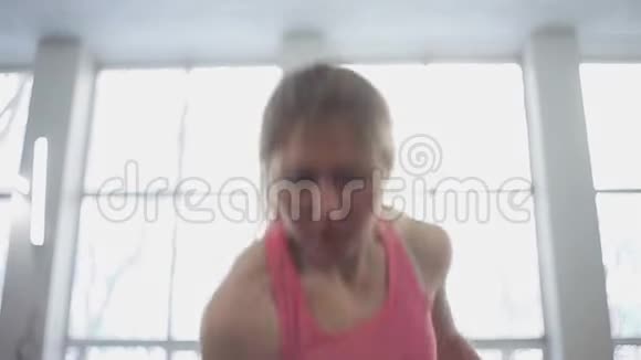年轻女子运动员表演一个挺举的水壶铃健身房里的女孩用水壶做健身运动视频的预览图