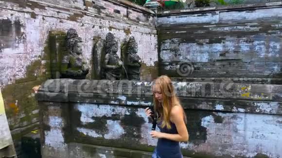 年轻的女摄影师和她的儿子参观巴厘岛上的GoaGajah或大象洞寺视频的预览图