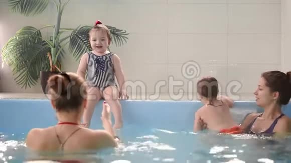 快乐的中年妈妈和可爱的可爱宝宝在游泳池游泳微笑的妈妈和小孩新生的女孩视频的预览图