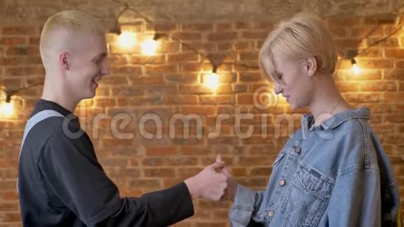 年轻迷人的时髦情侣玩拇指大战沟通观念砖背景视频的预览图