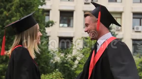 最好的朋友在毕业典礼上穿戴帽子拥抱微笑视频的预览图