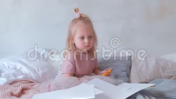 小可爱的金发女孩穿着粉红色的连衣裙手里拿着一只毛毡笔坐在纸上视频的预览图