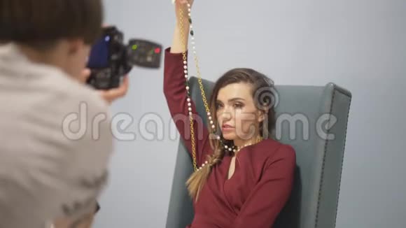 模特穿着红色连衣裙扶手椅上有一条金链图片会议视频的预览图