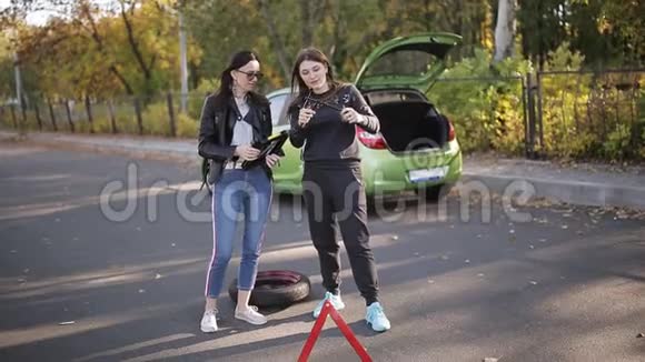 两个女人在路边试图用一个杰克从你的车上换轮胎咕哝着视频的预览图