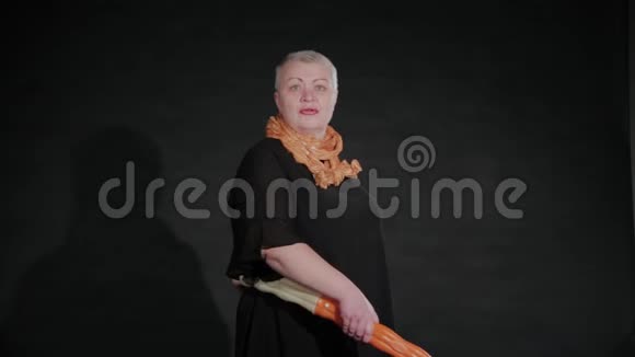 五十岁的女人在黑色背景上拧着呼啦圈视频的预览图