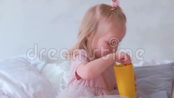 年轻迷人的金发女郎用毛毡笔吻着她穿着粉红色裙子的迷人小女儿视频的预览图