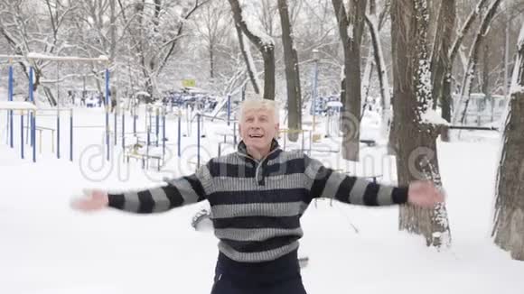 一位年长的欧洲男人在冬天做了一个早晨的户外热身跳在地上举起你的手拍手视频的预览图