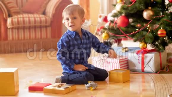4K录像显示小男孩因圣诞老人送的礼物而坐在圣诞树下哭泣视频的预览图