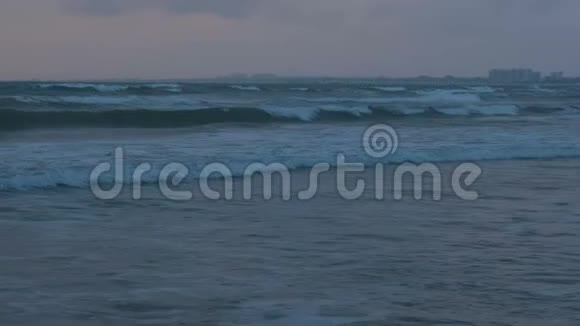 大风暴泡沫波在海中日落在黑暗的傍晚沿海小镇的背景视频的预览图