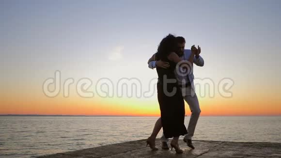 一对年轻迷人的夫妇在海边或海洋附近跳舞的拉丁巴哈塔的肖像日光背景夏日时光浪漫视频的预览图