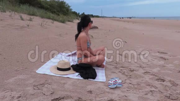 穿比基尼的女人坐在海滩上视频的预览图