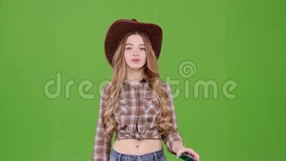 戴帽子的女牛仔在卡片上显示她的手指她为商品做广告绿色屏幕视频的预览图
