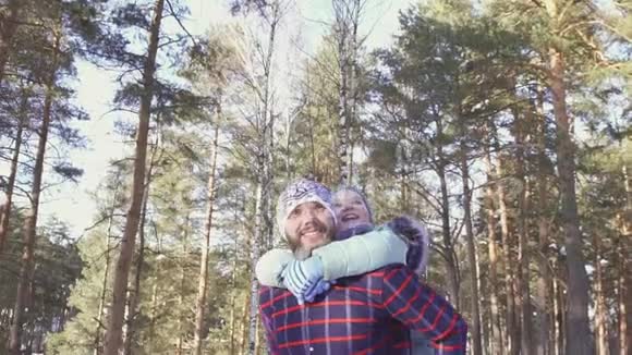 一个小女孩和她的父亲在阳光明媚的日子里漫步在冬天的森林里视频的预览图