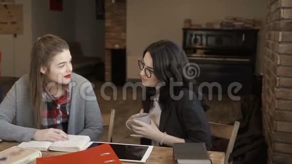年轻女孩和坐在桌边的朋友聊天视频的预览图