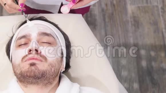 男人水疗的概念在一家美容院一个年轻人脸上戴着化妆面具视频的预览图