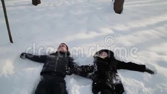美丽的年轻夫妇牵着手在雪地上玩得很开心城市冬季公园视频的预览图