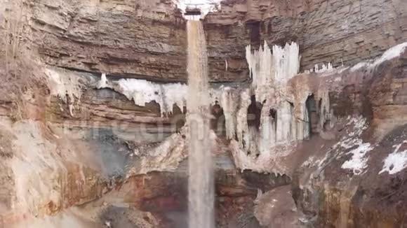 为黄色的小水流降落在悬崖峭壁和肮脏的冰在悬崖斜坡库存陡坡视频的预览图