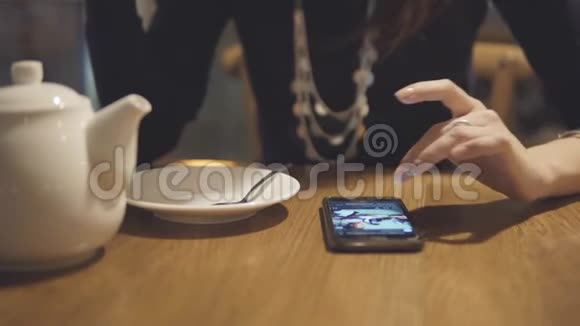 女孩用你的手指触摸屏幕女人在咖啡馆里用手机视频的预览图