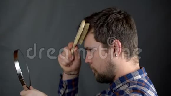 一个穿格子衬衫的男人在画室里对着镜子刷他的海兰德视频的预览图